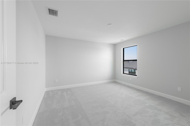 unfurnished room with baseboards, visible vents, and light colored carpet