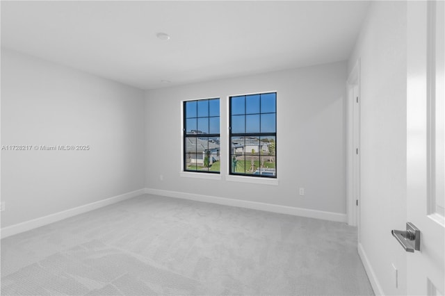 unfurnished room featuring light colored carpet and baseboards