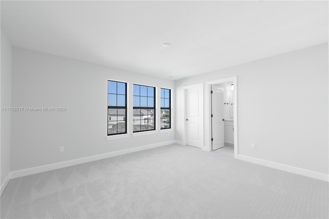 unfurnished room featuring baseboards and light colored carpet