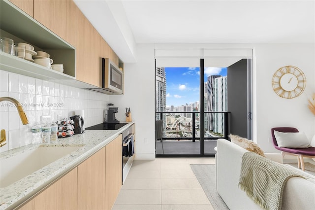 kitchen featuring light stone countertops, appliances with stainless steel finishes, decorative backsplash, sink, and light tile patterned flooring