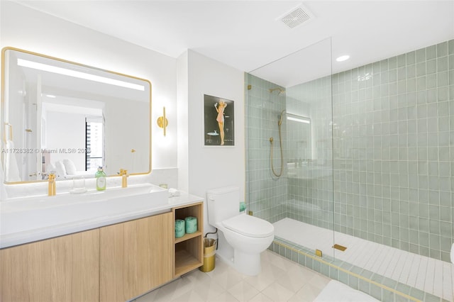 bathroom featuring toilet, a tile shower, tile patterned floors, and vanity