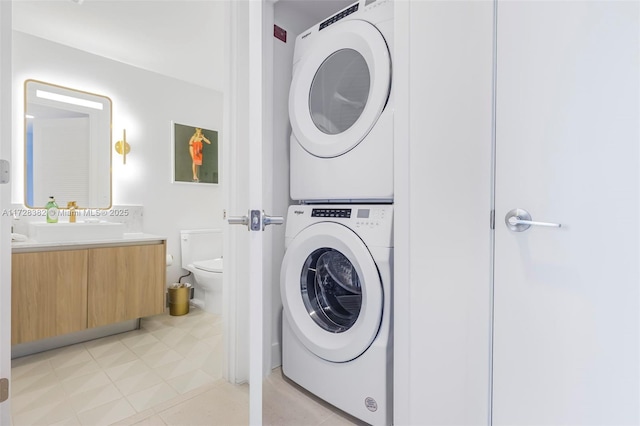 laundry room featuring light tile patterned floors, stacked washer / dryer, and sink