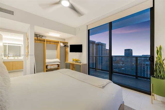 tiled bedroom featuring ceiling fan, access to exterior, ensuite bathroom, and floor to ceiling windows