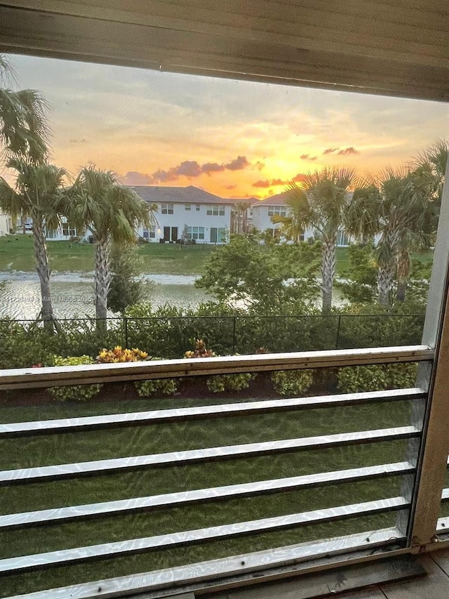 balcony at dusk featuring a water view