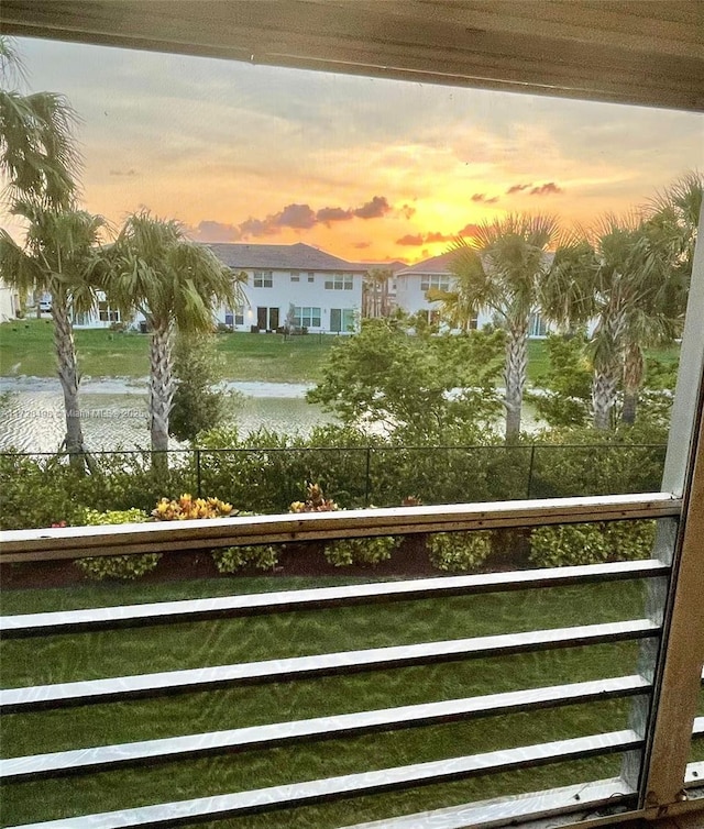 balcony at dusk featuring a water view