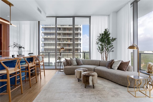 living room with plenty of natural light, wood-type flooring, and a wall of windows