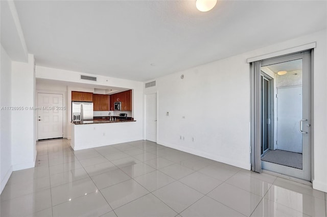 unfurnished living room featuring light tile patterned floors and sink