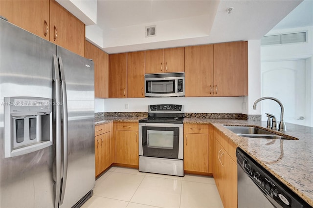 kitchen featuring light tile patterned floors, stainless steel appliances, light stone counters, and sink