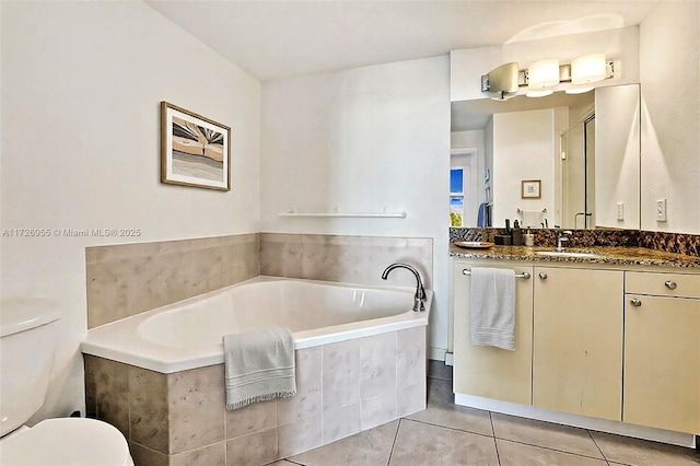 bathroom with toilet, vanity, tiled bath, and tile patterned floors