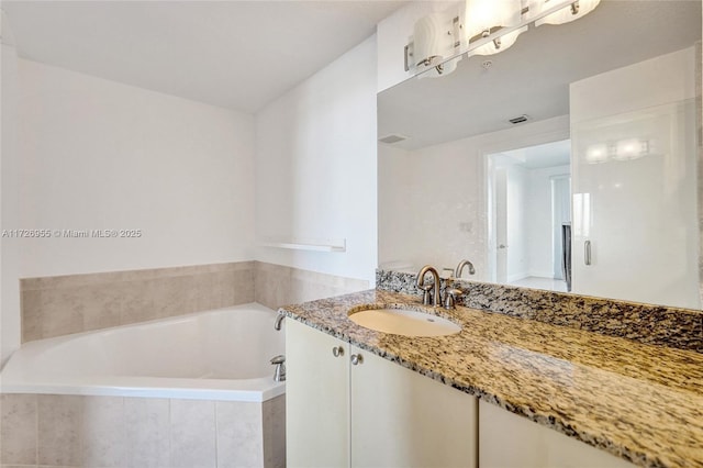 bathroom featuring a relaxing tiled tub and vanity