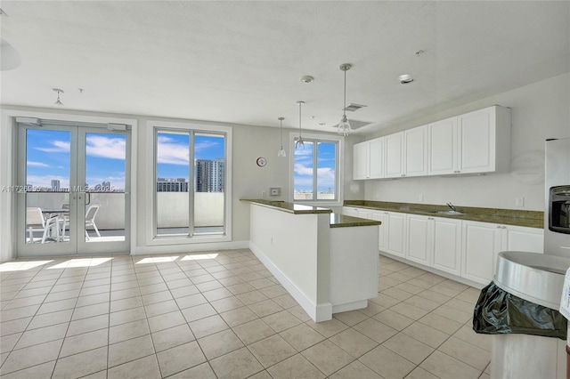 kitchen with white cabinets, sink, light tile patterned floors, and pendant lighting