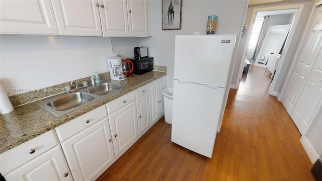 kitchen featuring sink, white cabinets, white fridge, and light wood-type flooring