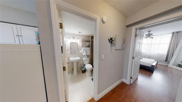 bathroom with toilet, ceiling fan, wood-type flooring, a textured ceiling, and sink