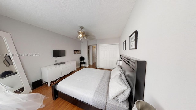 bedroom with a textured ceiling, ceiling fan, a closet, and light hardwood / wood-style flooring