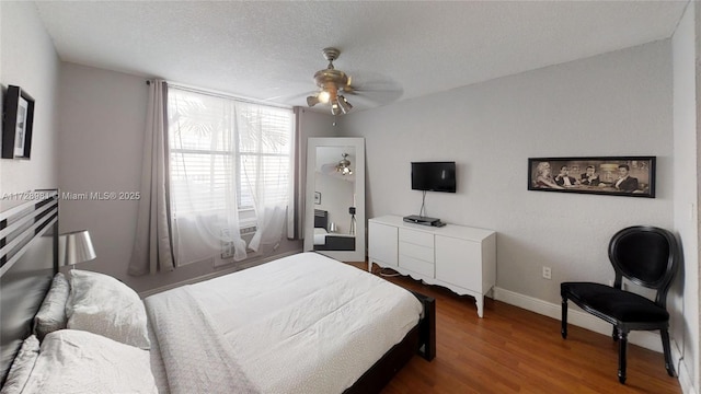 bedroom with ceiling fan, wood-type flooring, and a textured ceiling