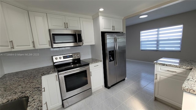 kitchen featuring appliances with stainless steel finishes, backsplash, light tile patterned flooring, stone countertops, and white cabinets