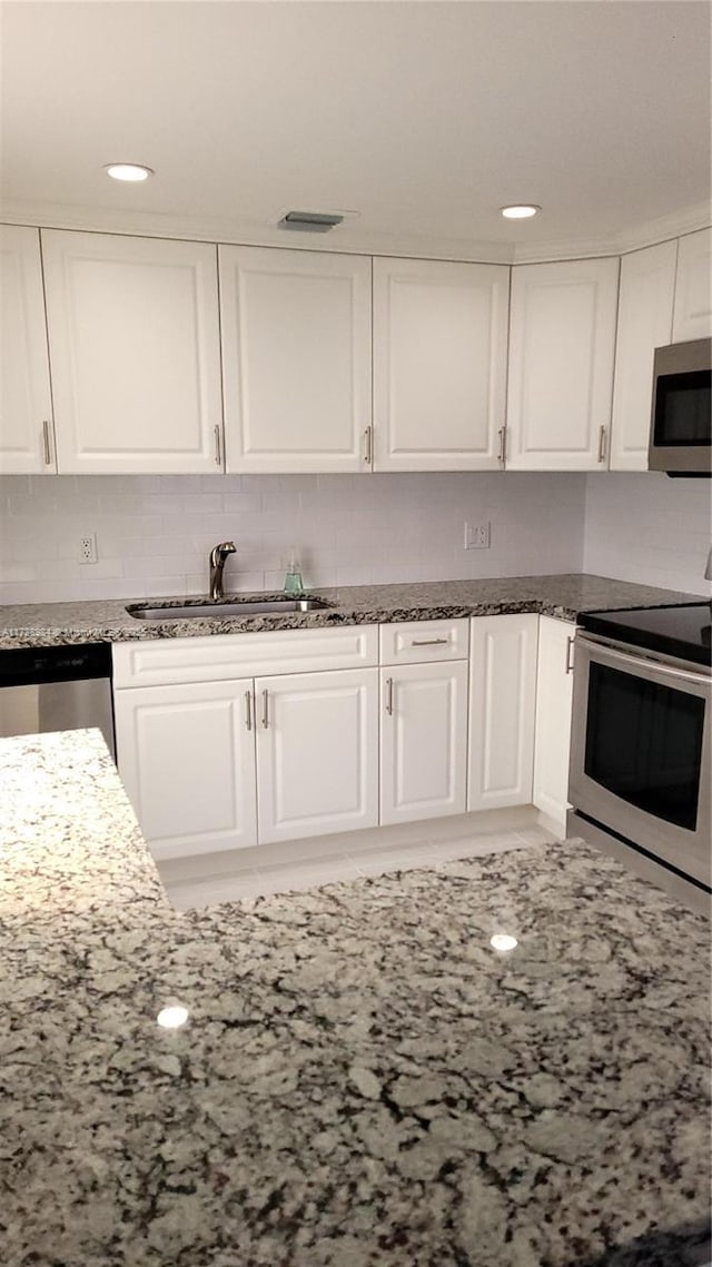 kitchen featuring sink, white cabinets, stainless steel appliances, and stone counters