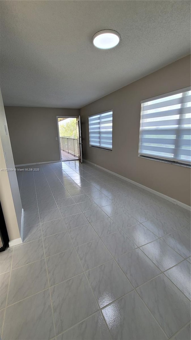 tiled spare room featuring a textured ceiling