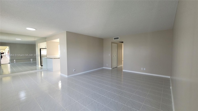 tiled empty room featuring a textured ceiling