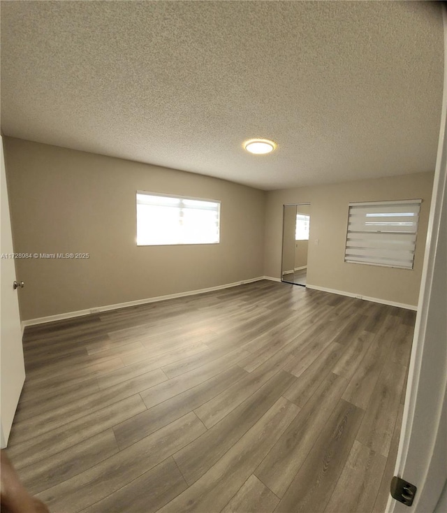 unfurnished room with a textured ceiling and wood-type flooring