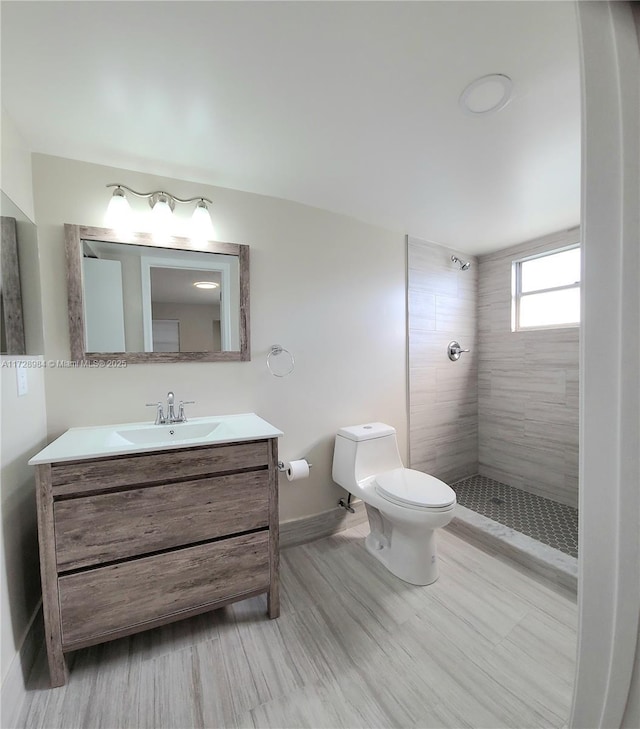 bathroom featuring wood-type flooring, toilet, vanity, and a tile shower