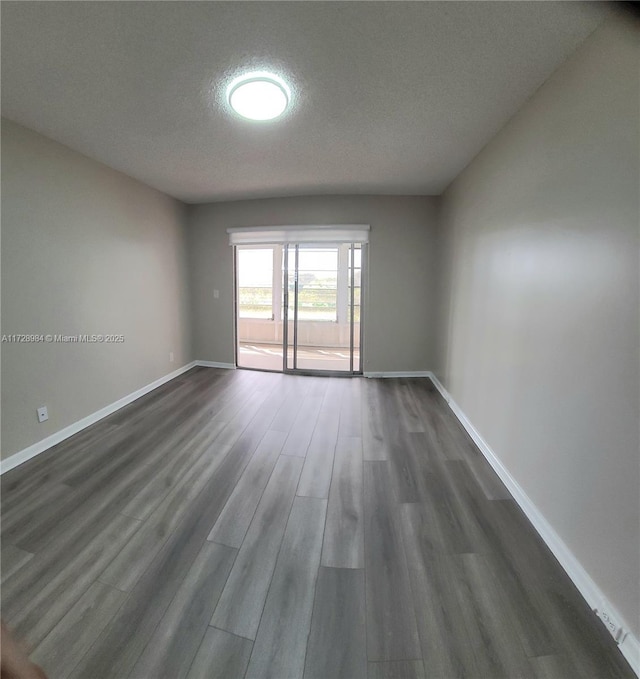 unfurnished room featuring dark wood-type flooring and a textured ceiling