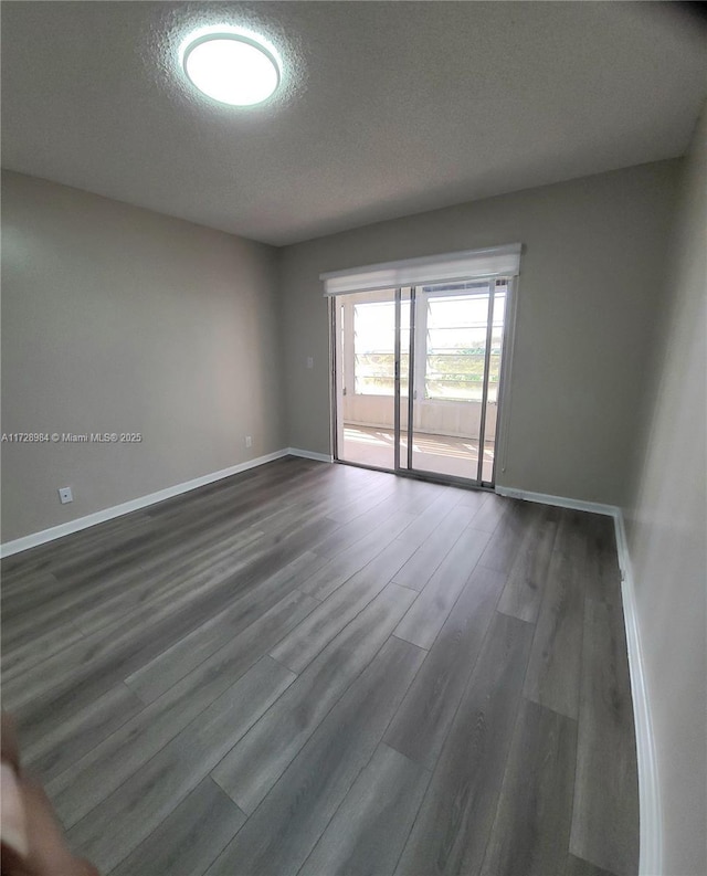 spare room with a textured ceiling and dark hardwood / wood-style flooring