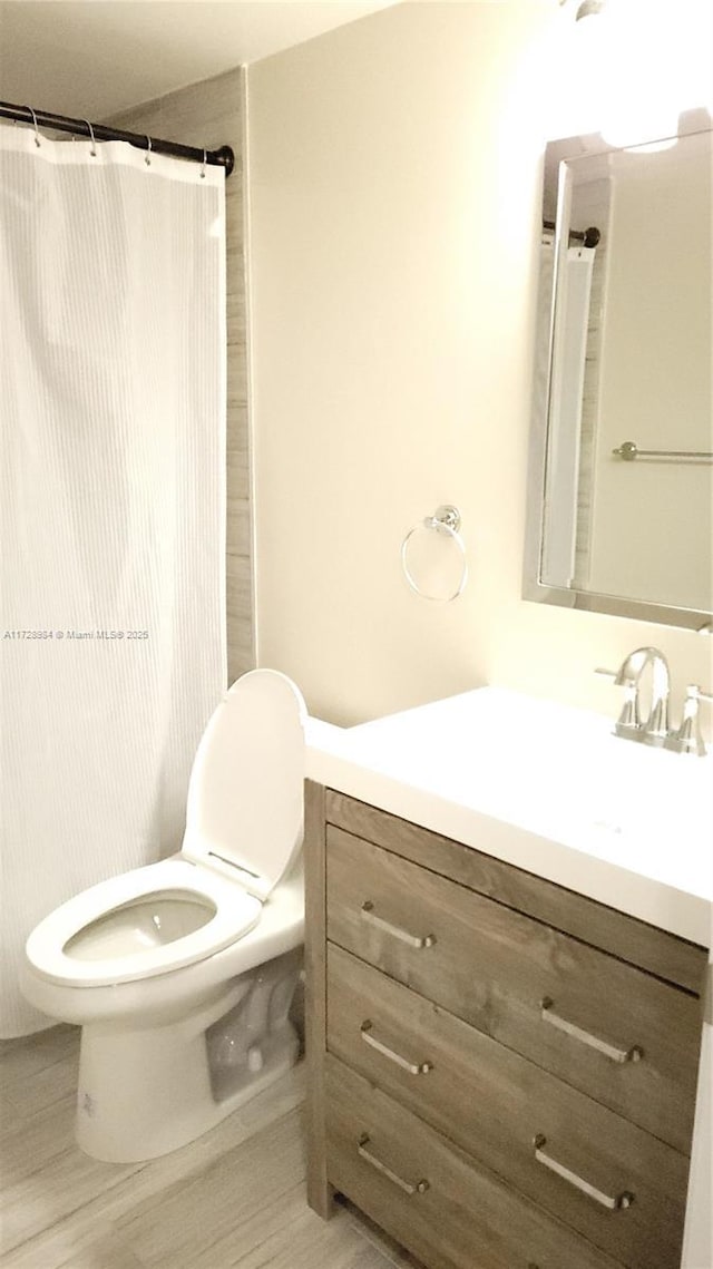 bathroom with toilet, vanity, and curtained shower