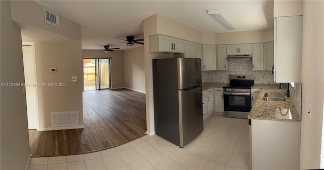 kitchen with sink, appliances with stainless steel finishes, ceiling fan, light stone countertops, and decorative backsplash