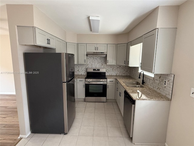 kitchen with sink, gray cabinets, appliances with stainless steel finishes, light stone counters, and tasteful backsplash