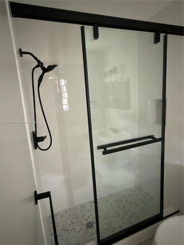 bathroom featuring toilet and a shower with shower door