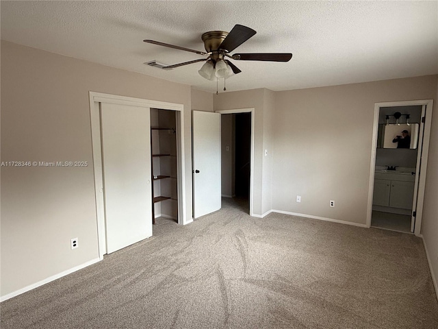 unfurnished bedroom featuring connected bathroom, carpet, ceiling fan, a textured ceiling, and a closet