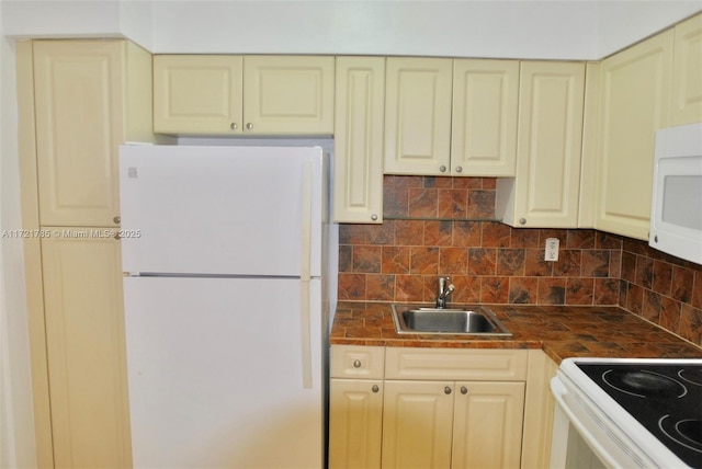 kitchen with decorative backsplash, sink, cream cabinetry, and white appliances