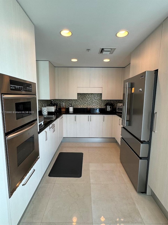 kitchen with light tile patterned flooring, appliances with stainless steel finishes, and tasteful backsplash