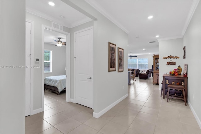 hallway with a wealth of natural light, ornamental molding, and light tile patterned flooring