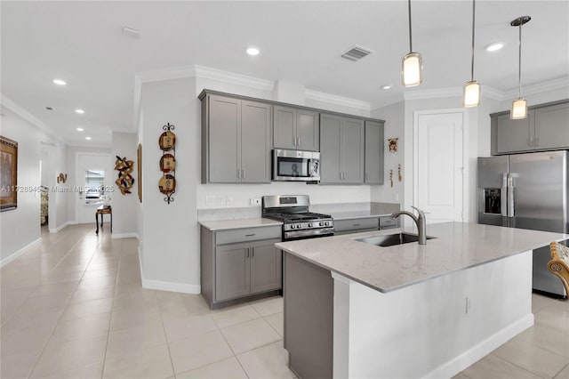 kitchen featuring a center island with sink, gray cabinets, appliances with stainless steel finishes, light stone countertops, and sink