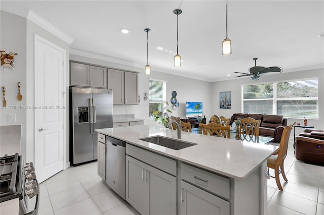 kitchen with an island with sink, stainless steel appliances, gray cabinetry, hanging light fixtures, and sink