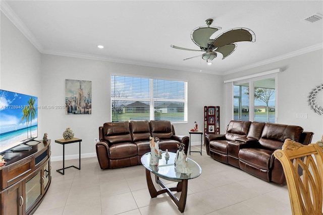 living room with ceiling fan, light tile patterned flooring, ornamental molding, and a healthy amount of sunlight