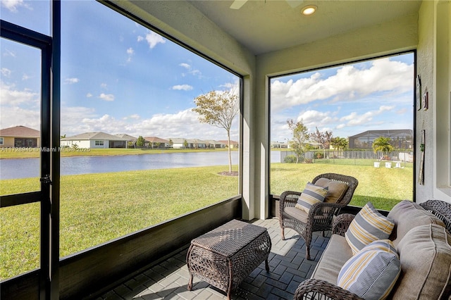 sunroom featuring ceiling fan and a water view