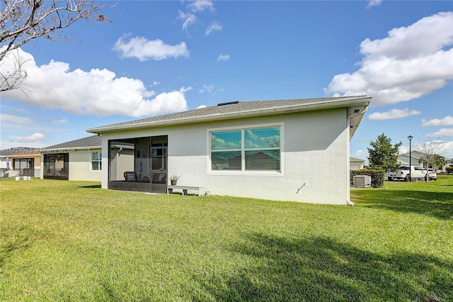 rear view of property with a sunroom, cooling unit, and a lawn