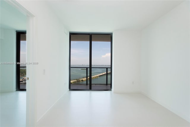 spare room featuring a wall of windows and a water view