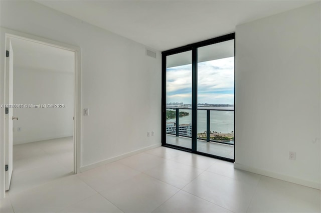 spare room with expansive windows and a water view