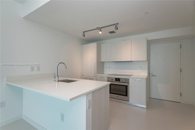 kitchen with rail lighting, kitchen peninsula, black electric cooktop, oven, and sink