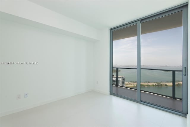 spare room with a water view and expansive windows