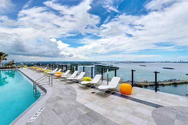 view of pool with a water view and a patio