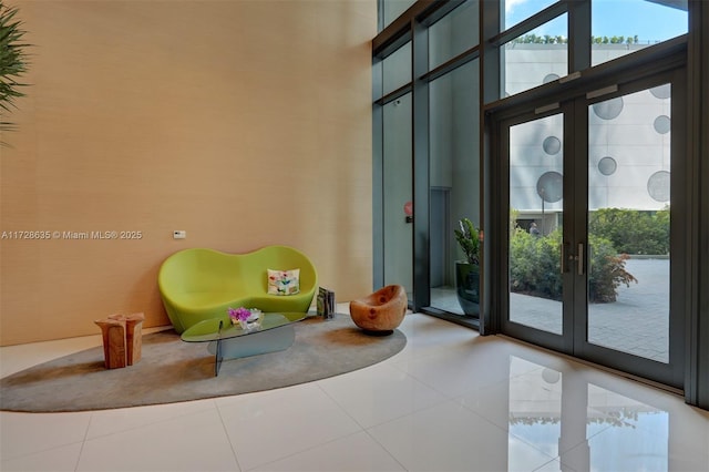 unfurnished room featuring a high ceiling, tile patterned floors, expansive windows, and french doors