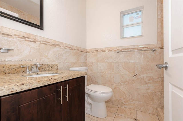 bathroom with toilet, vanity, tile walls, and tile patterned flooring