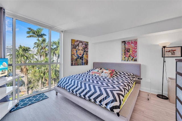 bedroom with floor to ceiling windows and hardwood / wood-style flooring