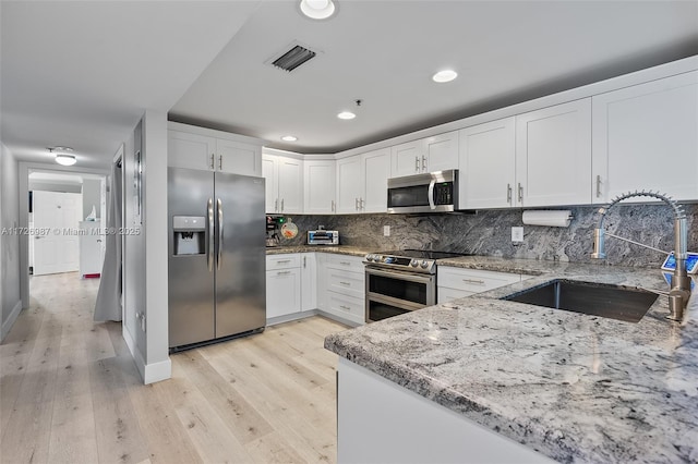 1400 Salzedo St Unit 301, Coral Gables, FL 33134 - kitchen with appliances with stainless steel finishes, light stone counters, light wood finished floors, white cabinetry, and recessed lighting