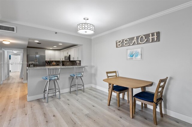 kitchen featuring white cabinets, stainless steel appliances, backsplash, kitchen peninsula, and a breakfast bar area